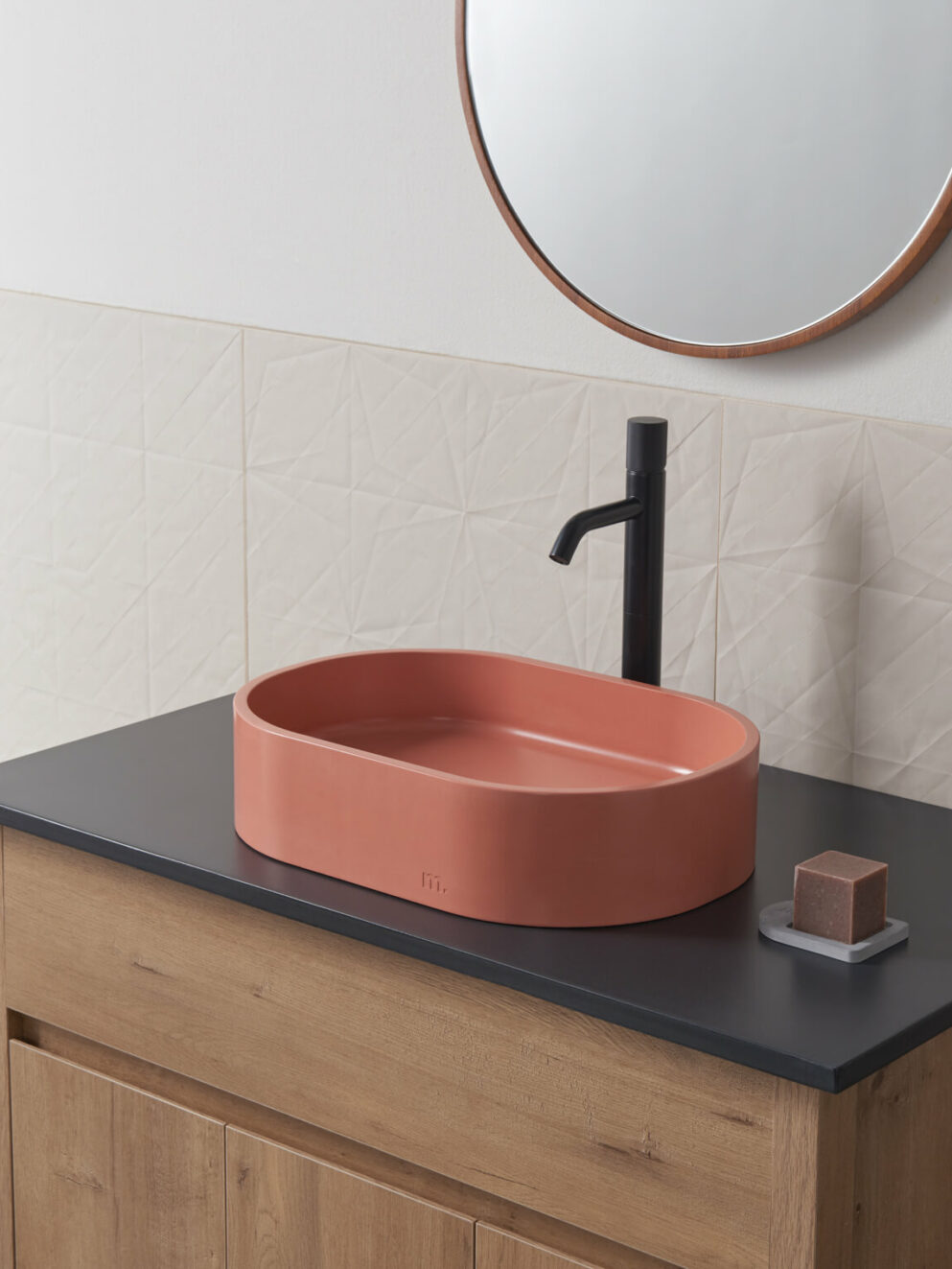 the Parro(pill shaped) sink in mousse set in a calming modern bathroom setting with a black faucet and wooden cabinet