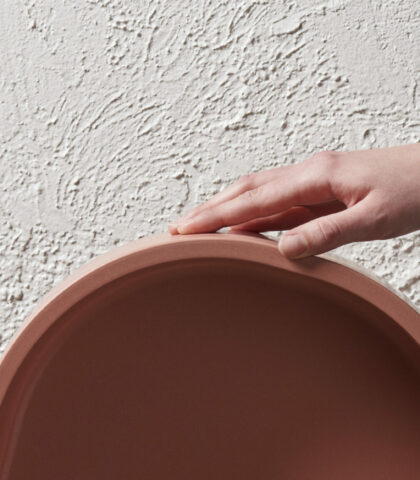 hand touching curvature on pink concrete sink basin